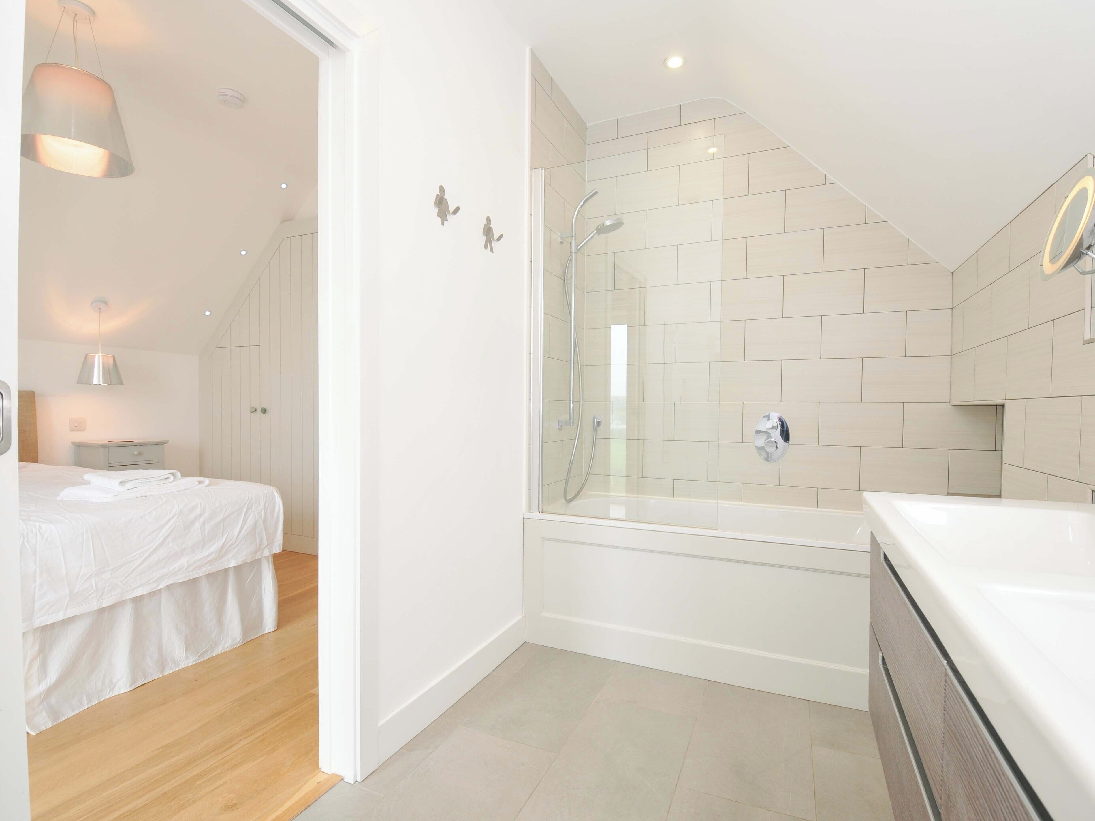 A modern bathroom with a glass-enclosed shower, a white bathtub, and a large mirror.