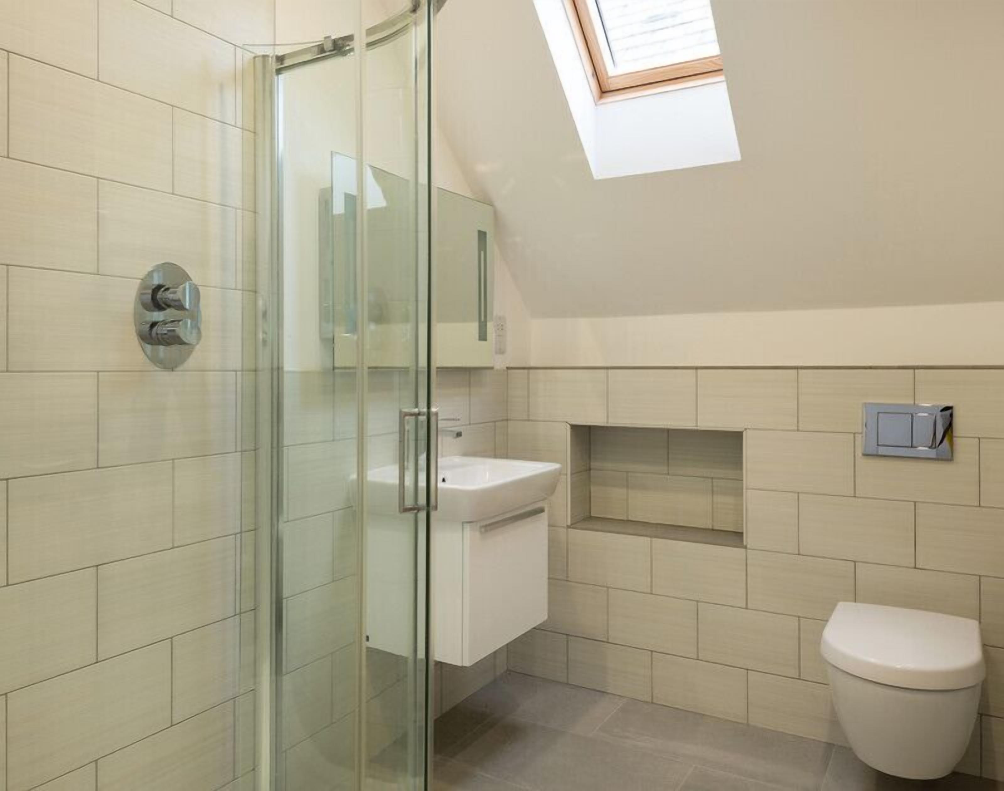 A modern bathroom with a glass shower enclosure, a white sink, and a toilet.