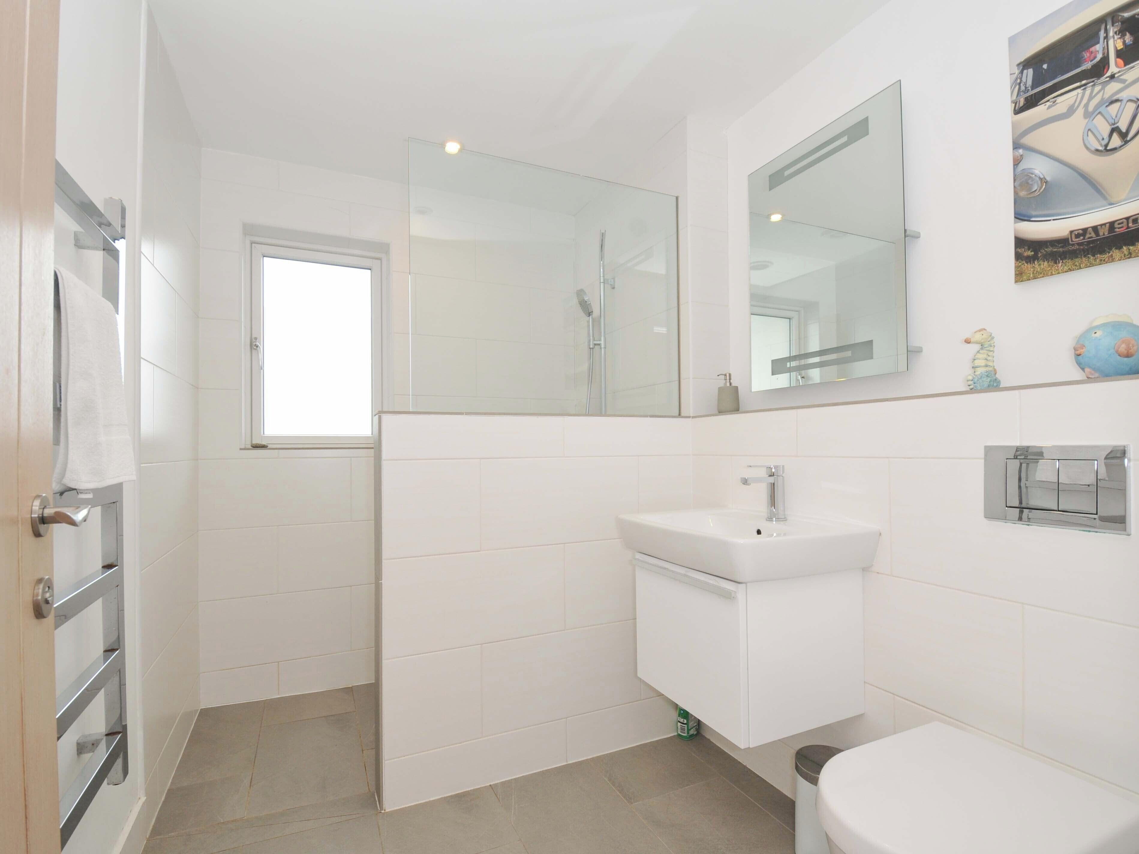 A modern bathroom with a white sink, mirror, and toilet.