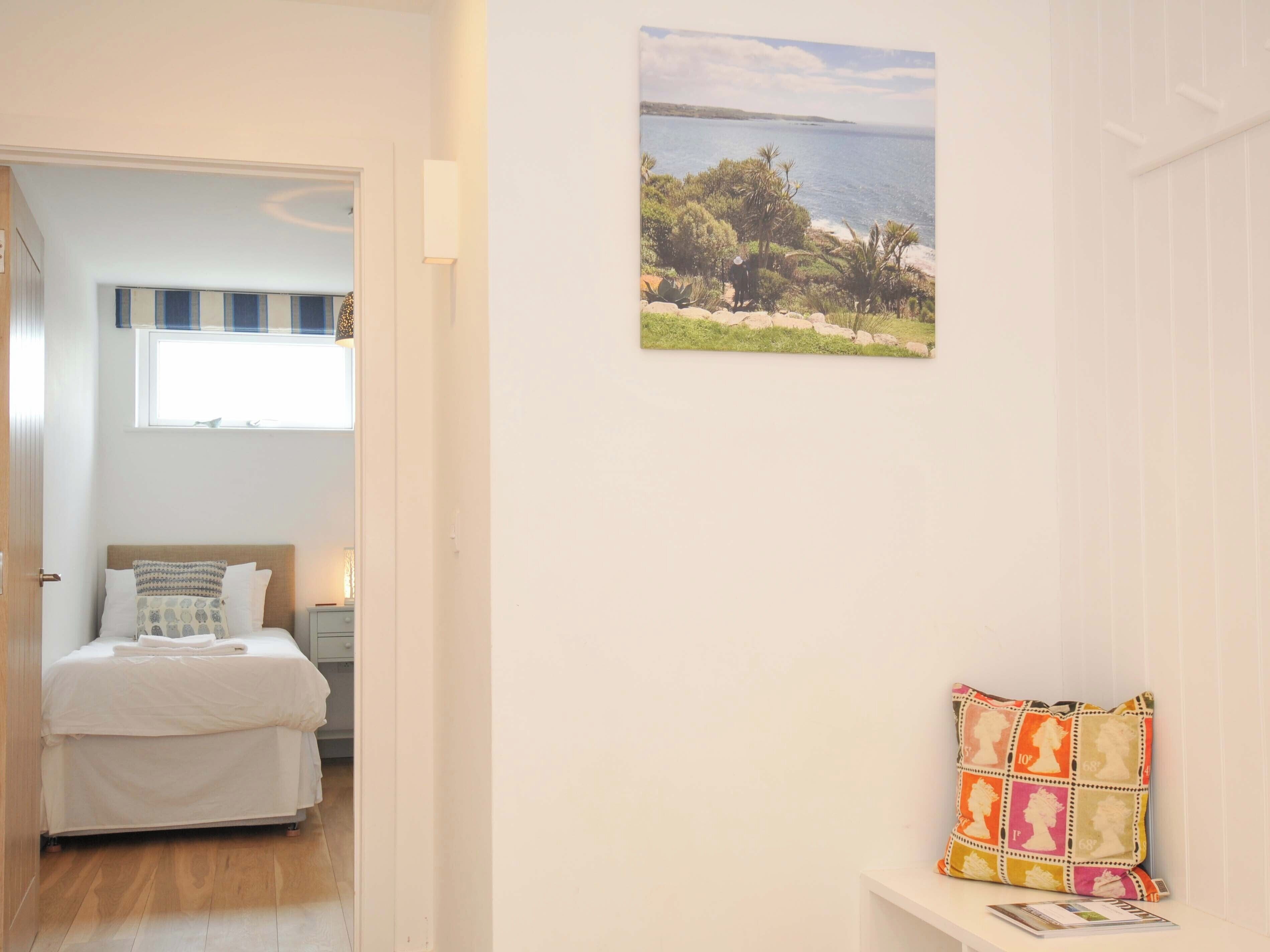 Une chambre à coucher avec un lit, une fenêtre, un tableau accroché au mur et une table de chevet.
