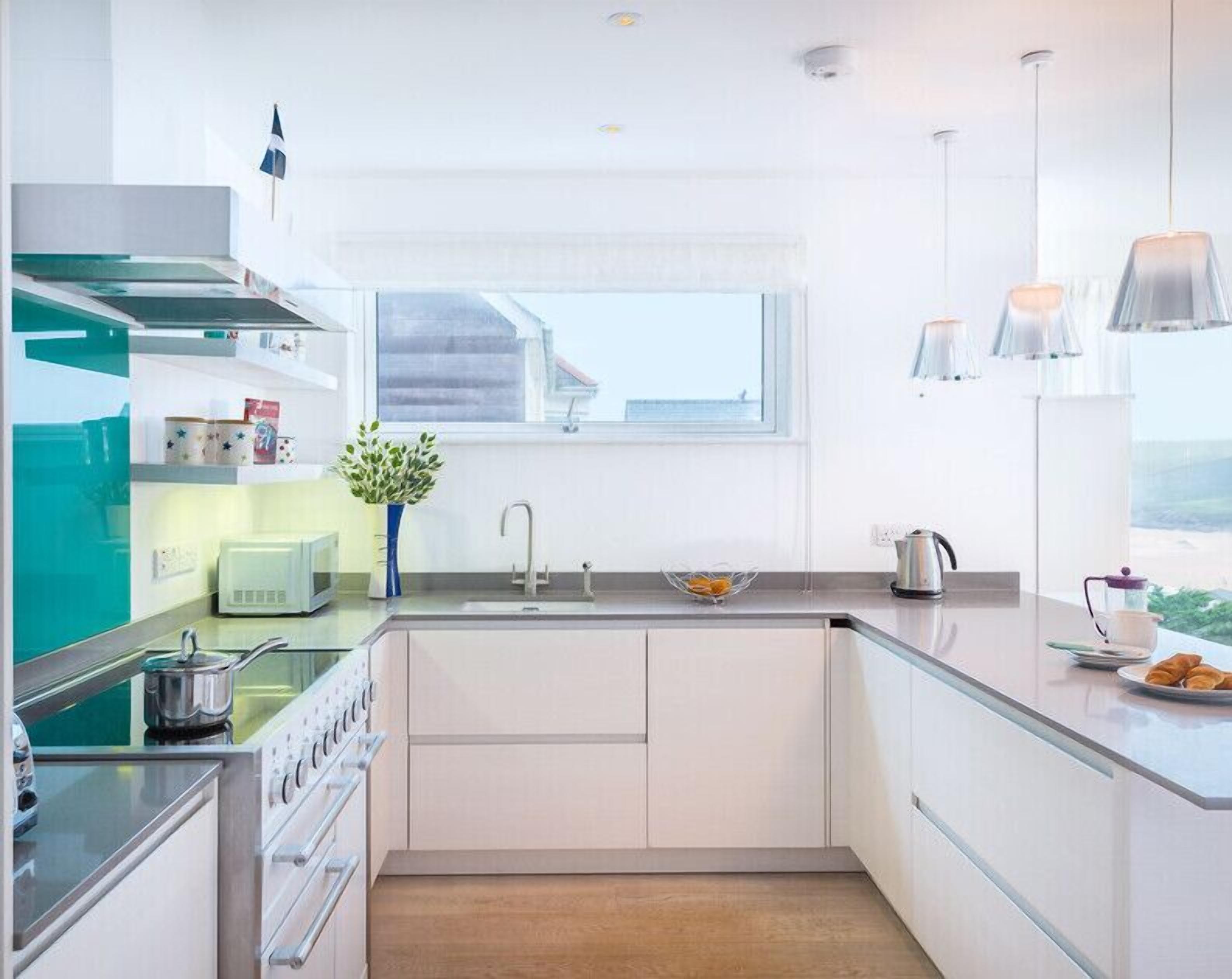 A modern kitchen with a built-in stove, a sink, and a window overlooking a residential area.