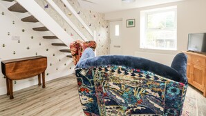 Une pièce avec un escalier, une armoire en bois, un téléviseur et un tapis à motifs.
