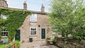 Une maison en pierre avec une porte verte, une fenêtre à cadre blanc et un mur en pierre.