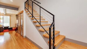 Una escalera moderna con escalones de madera y barandilla metálica, que conduce a un piso superior.