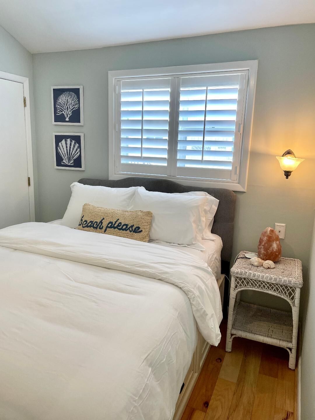 A bedroom with a bed, a nightstand with a lamp, and two wall art pieces.