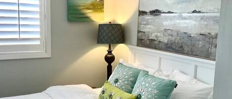 Un dormitorio con cama, lámpara y un cuadro en la pared.