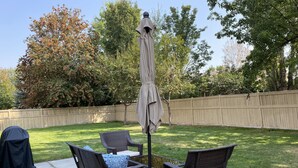 A patio with wicker furniture, a covered umbrella, and a concrete floor. - Just like home, clean in great family friendly location (Boise)