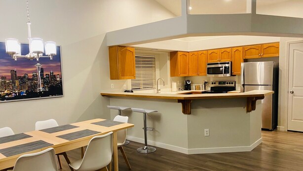 A modern kitchen with wooden cabinets, a stainless steel refrigerator, and a built-in oven. - Just like home, clean in great family friendly location (Boise)