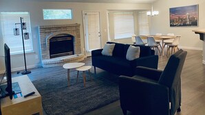 A living room with a fireplace, a sofa, a coffee table, and a dining area with chairs. - Just like home, clean in great family friendly location (Boise)