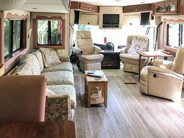 Un interior de caravana acogedor con sofá, sillas, una mesita y chimenea.