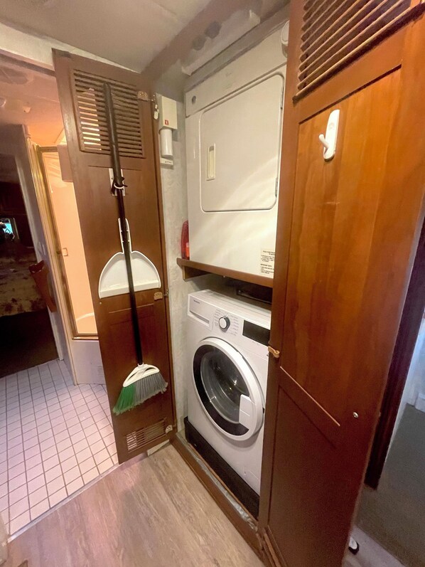 A compact laundry room with a washing machine, a drying rack, and a broom.