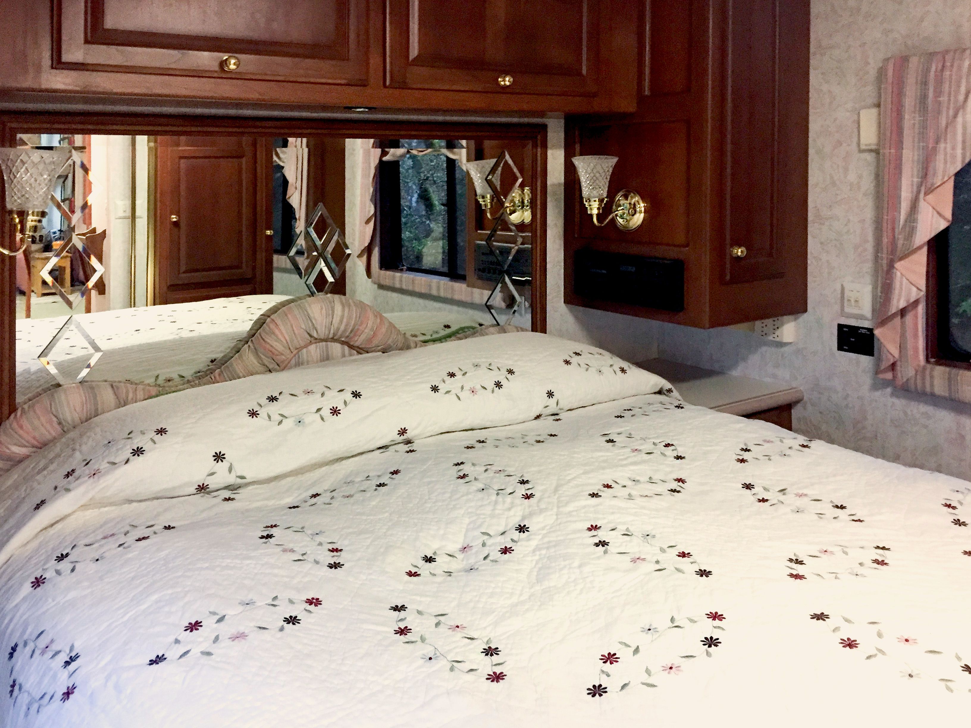 Een slaapkamer met een groot bed, een houten hoofdbord en een nachtkastje met een lamp.