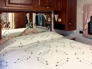 Un dormitorio con una cama grande, cabecera de madera y una mesita de noche con lámpara.