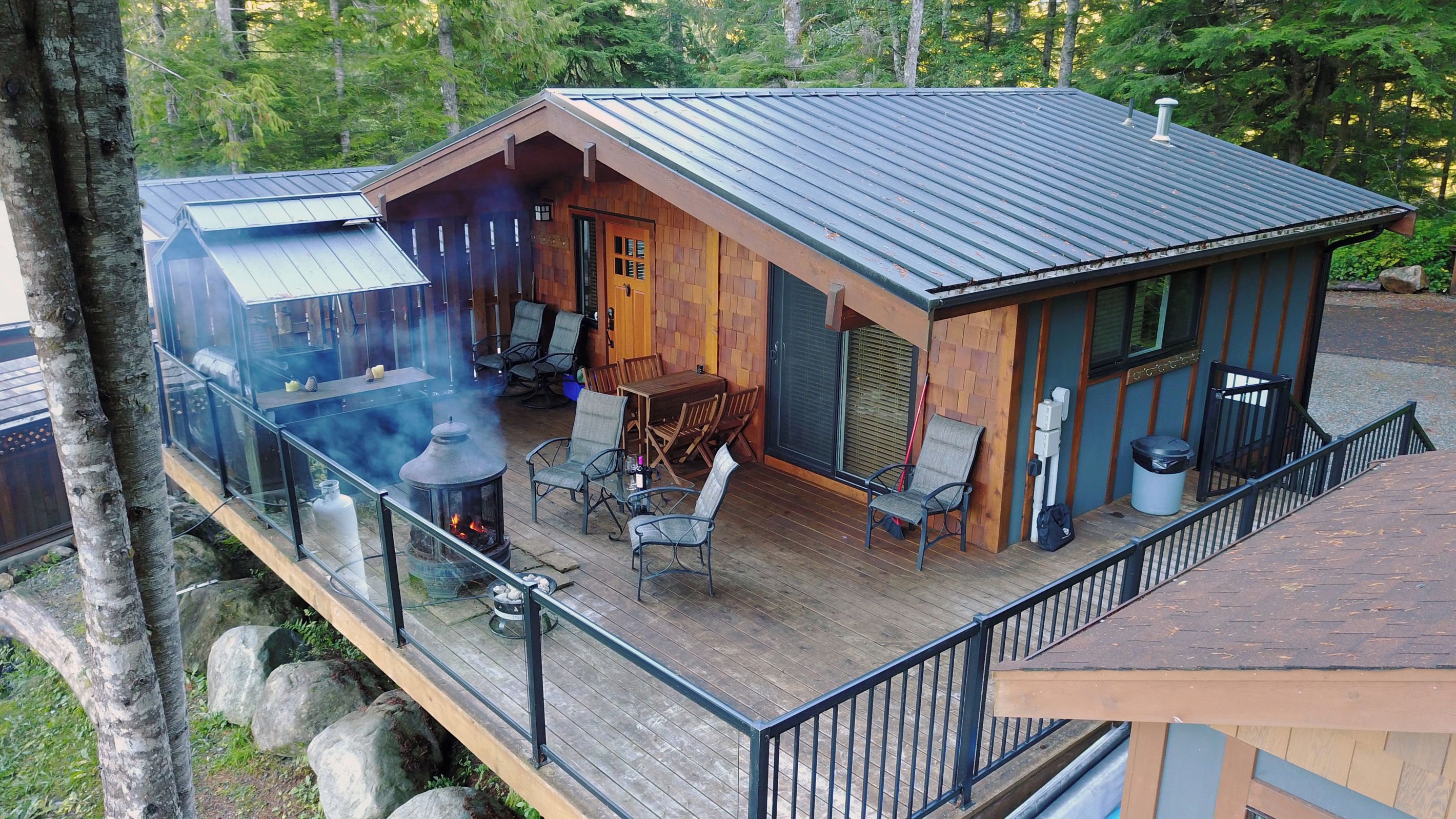 Une cabane dotée d’une terrasse, de coins salon extérieurs et d’un foyer.
