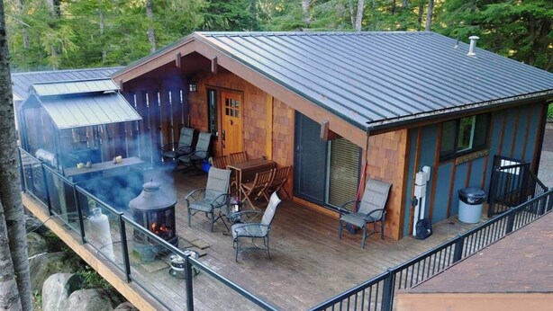 A cabin with a deck, outdoor seating, and a wood-burning stove. - The Great Escape - Port Renfrew (Port Renfrew)