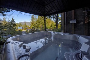 A hot tub with a view of a forest and mountains.