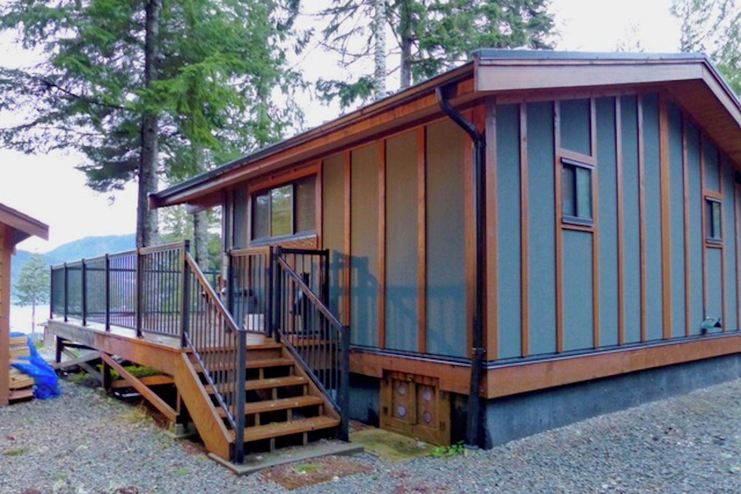 A cabin with a wooden deck, a staircase, and a large window.