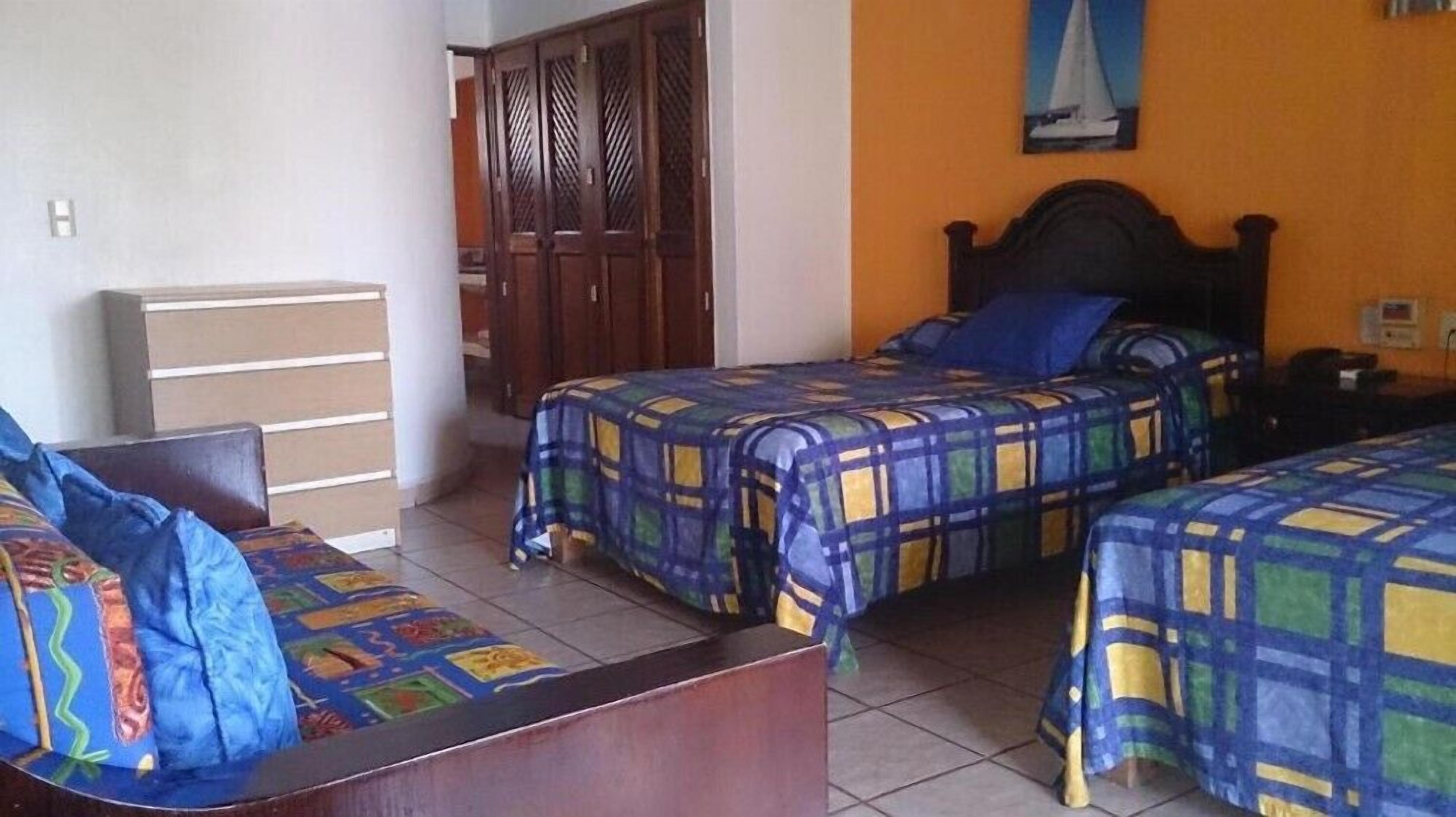 A room with two beds, a wooden wardrobe, a desk, and a chair.