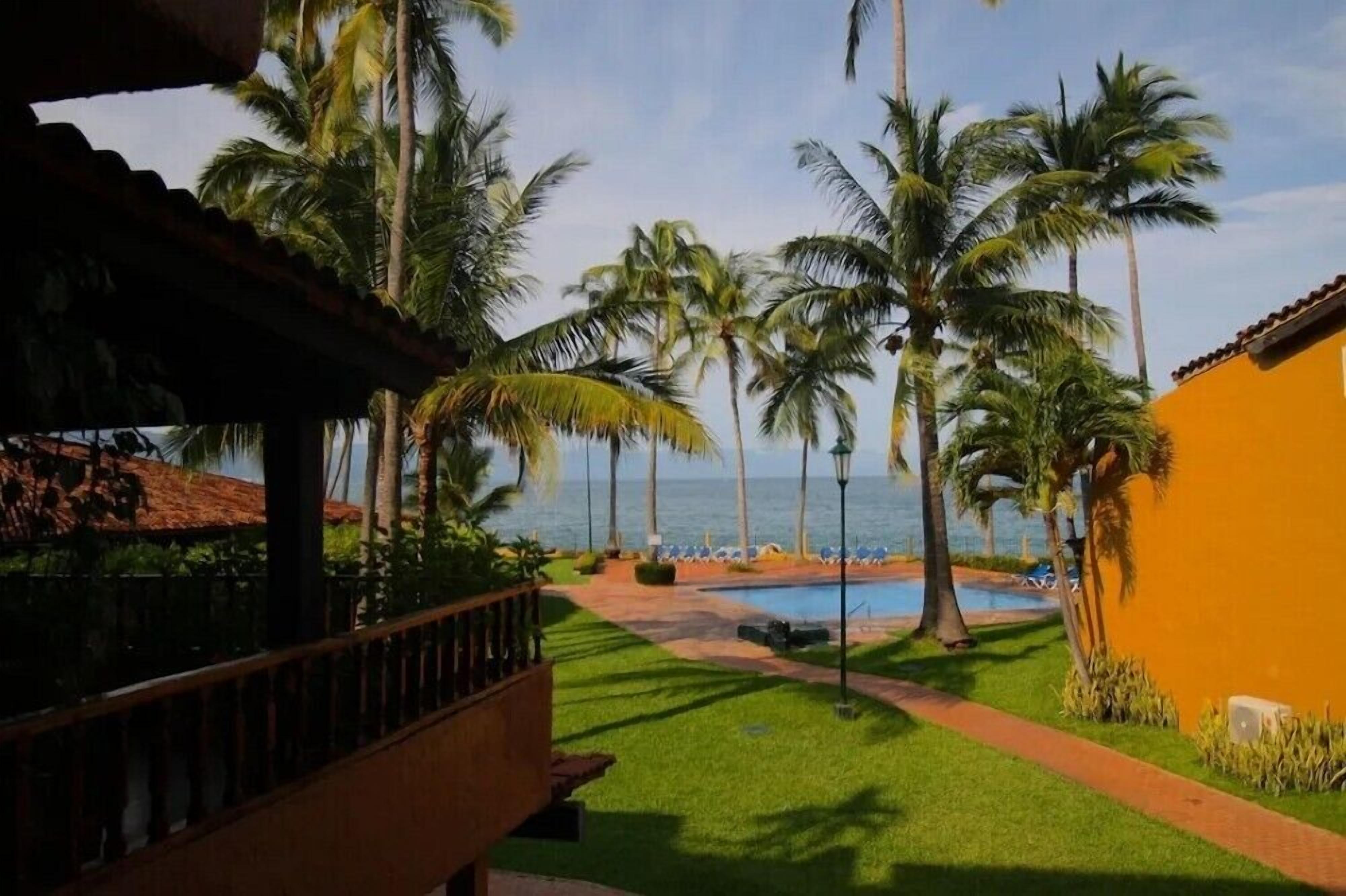 A pool area with palm trees and a view of the ocean.