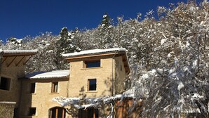 Un edificio de piedra con techo nevado y un patio con muebles de exterior.