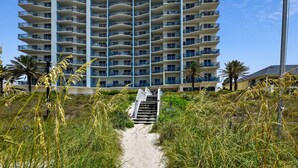 A pathway leading to a high-rise building with multiple balconies. - Beautiful 17th Floor Views! Free Activities + Summer Deals!! (Panama City Beach)