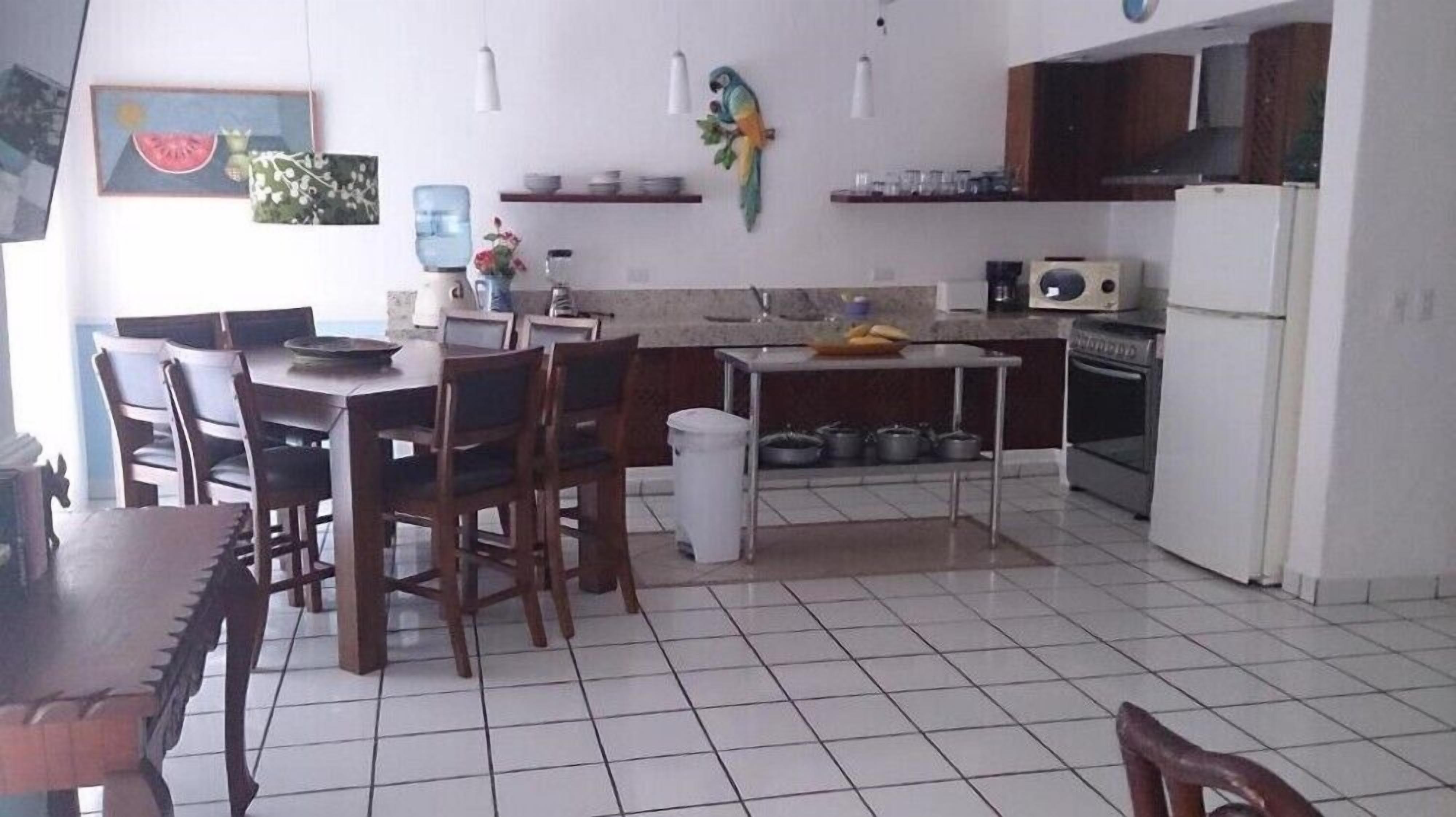 Eine Küche mit Esstisch, Stühlen, einem Kühlschrank und einer Mikrowelle.