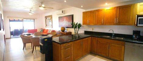 A modern kitchen with wooden cabinets, a black countertop, and a built-in dishwasher.