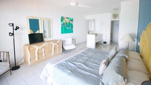 A bedroom with a bed, bedside table, a mirror, a ceiling fan, and a TV.