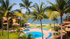 A resort with a pool area, palm trees, and a view of the ocean.