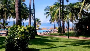Een resort met een zwembad, palmbomen en uitzicht op de oceaan.
