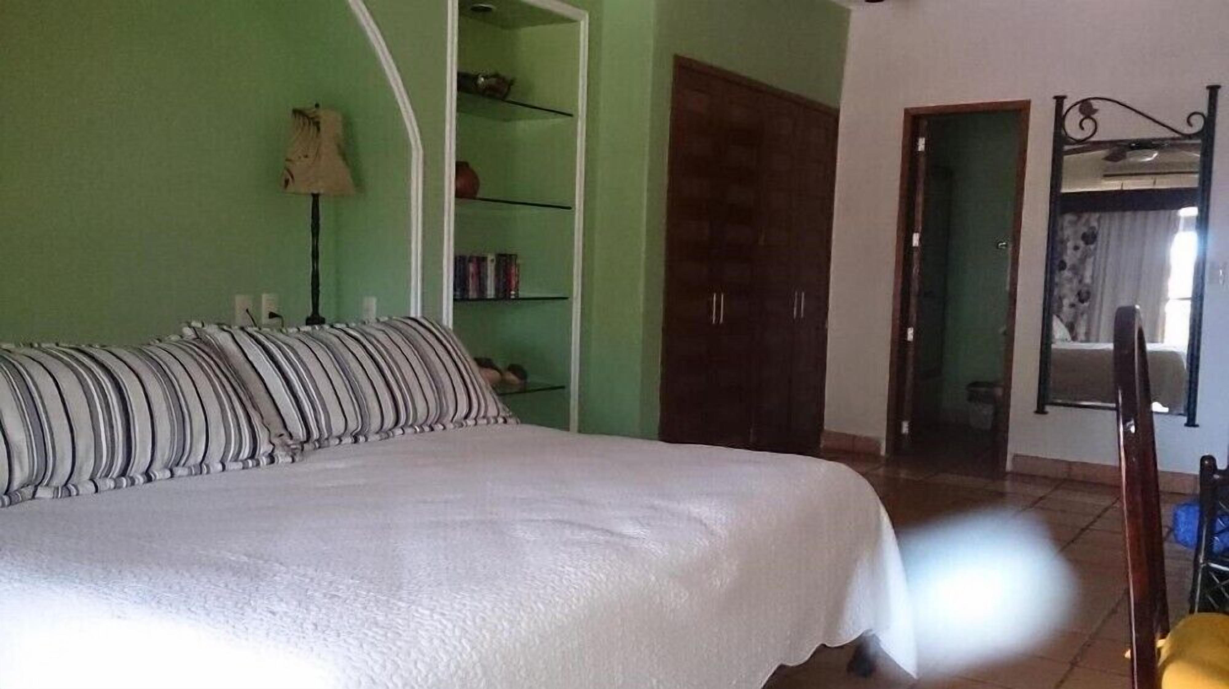 Une chambre à coucher avec un lit, une armoire, un miroir et une étagère remplie de livres.