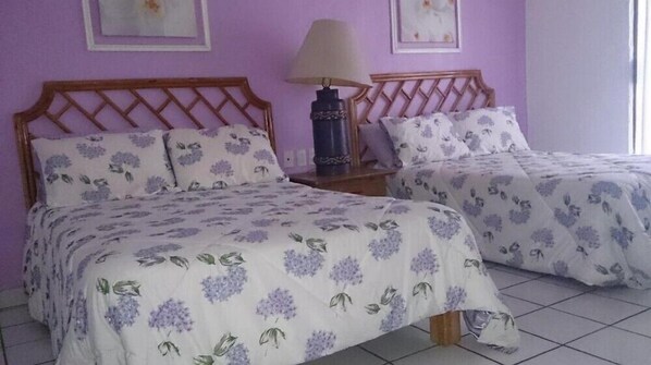 Two twin beds with floral bedding, a nightstand with a lamp, and a wall with framed artwork. - Los Tules Private 2BR Condo with Pool and Local Attractions (Puerto Vallarta)