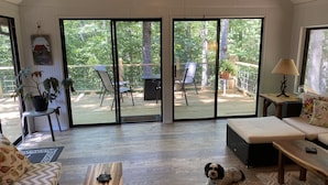 Uma sala de estar espaçosa com uma grande porta de vidro deslizante que dá para um deck ao ar livre.