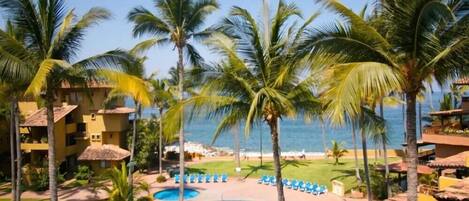 Un resort con piscina, palmeras y vista al océano.