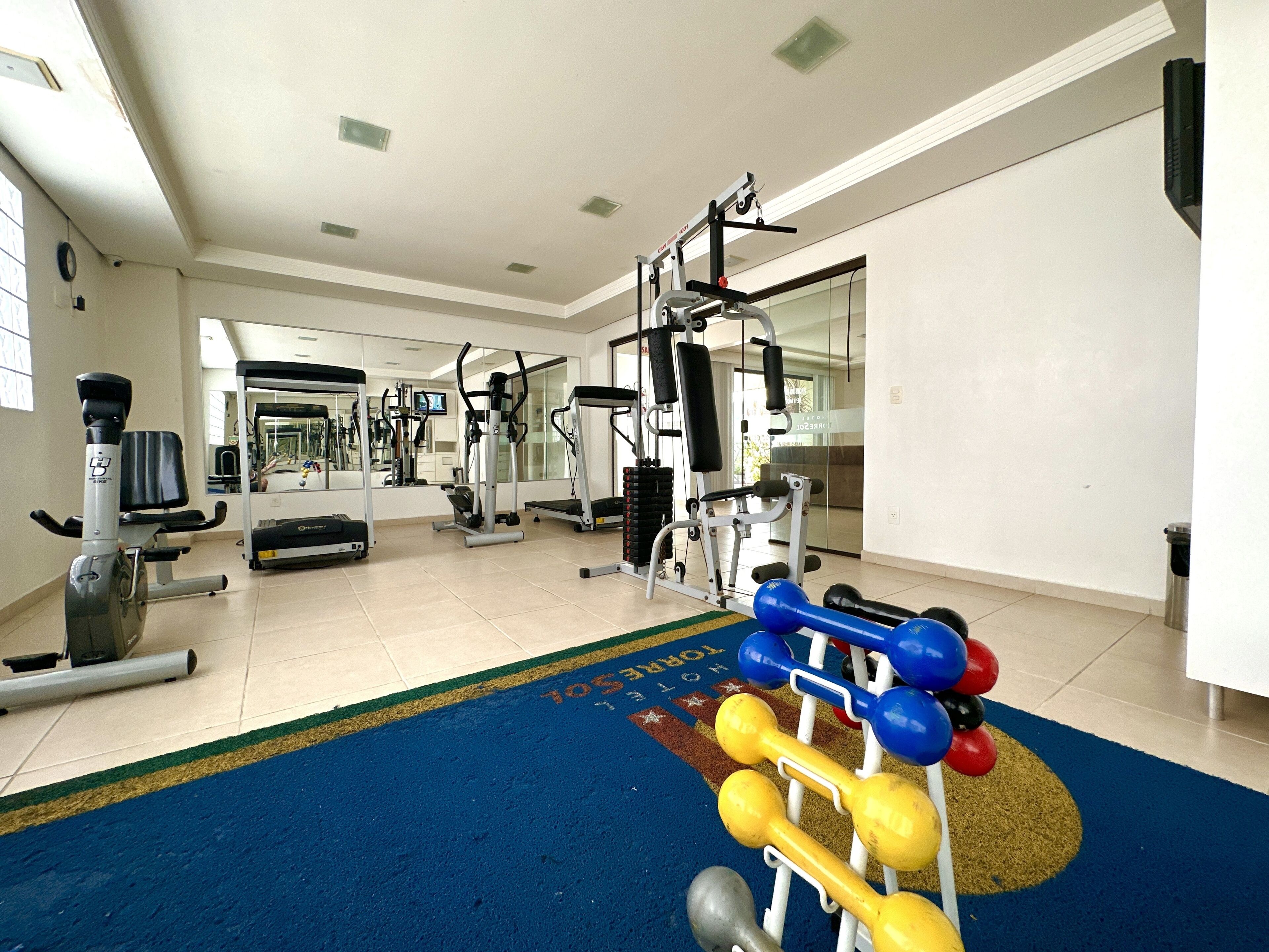 A gym with exercise equipment, a blue mat, and a mirror.