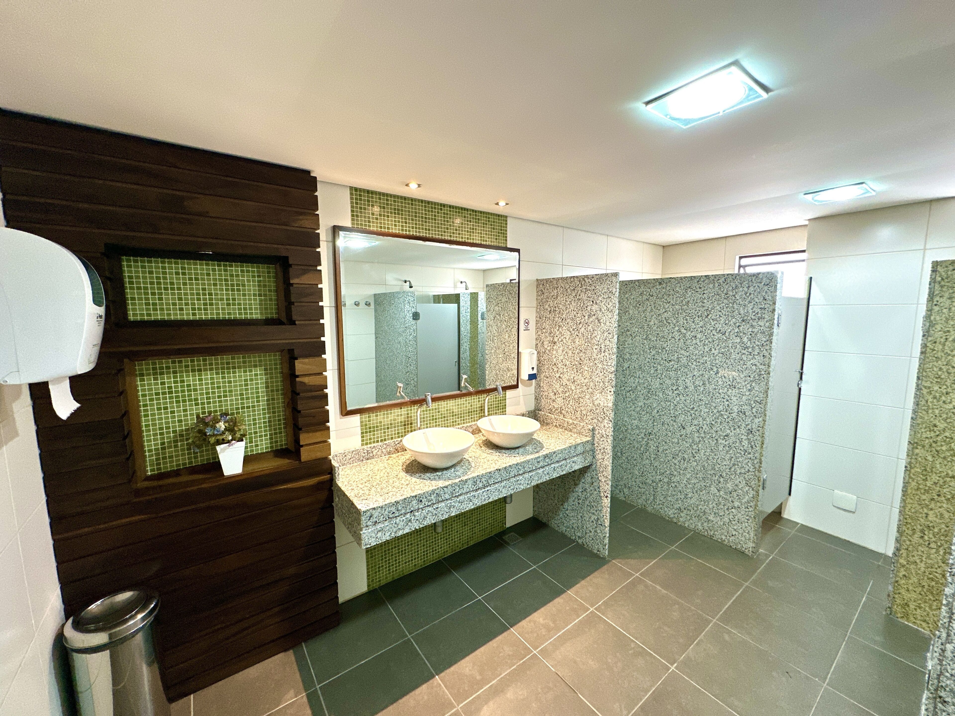 A modern bathroom with a large mirror, two sinks, and a shower area.