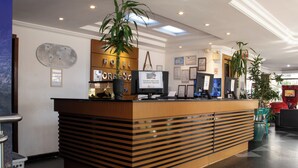 Un comptoir d’accueil d’hôtel doté d’un écran numérique, de certificats encadrés et d’une carte du monde.