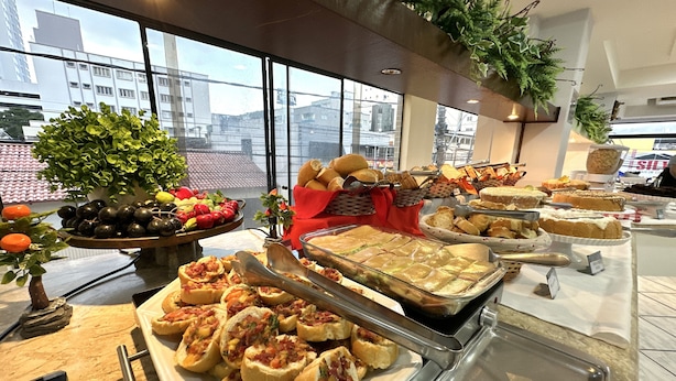 Un buffet proposant une variété de plats, notamment du pain, des pâtisseries et des fruits.
