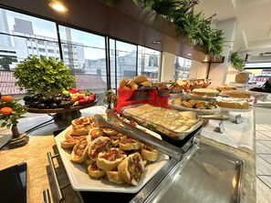 A buffet with various food items, including bread, pastries, and fruits.