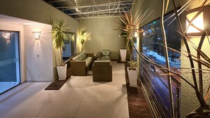 Un intérieur moderne avec un plafond haut, un coin salon et des plantes en pot.