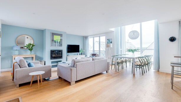 Ein modernes Wohnzimmer mit Sofa, Fernseher und Essbereich.