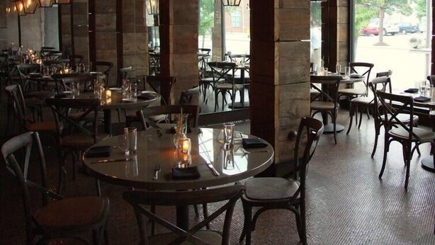 Un restaurante con faroles hexagonales colgando del techo, mesas redondas y sillas dispuestas para comer.