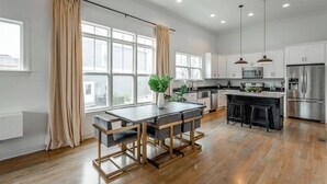 Una cocina moderna con una isla central, piso de madera e iluminación colgante.