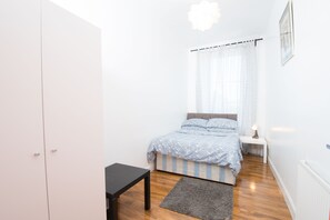 A bedroom with a bed, bedside table, and a wardrobe. - 7 Bedroom Townhouse (Edinburgh)