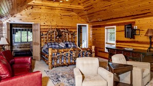 Ein Holzblockhaus-Interieur mit einem Bett, einem roten Ledersofa und einem Esstisch.