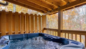 Een hottub onder een houten pergola met een houten omheining op de achtergrond.