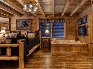L’intérieur d’une cabine comprend un lit en bois, une petite table avec une lampe, une baignoire et une fenêtre avec des stores.