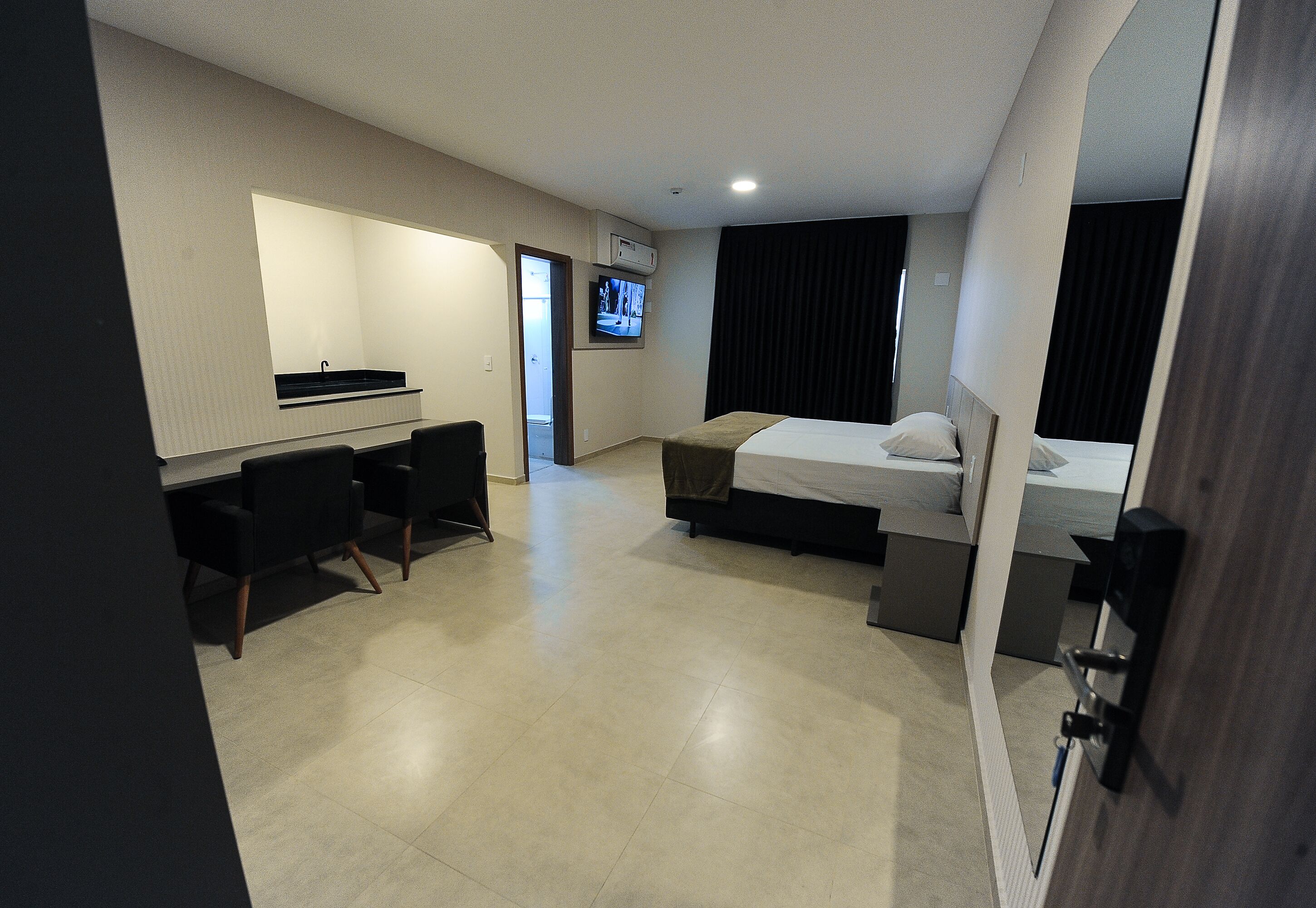 A hotel room with a bed, a desk, and a TV.