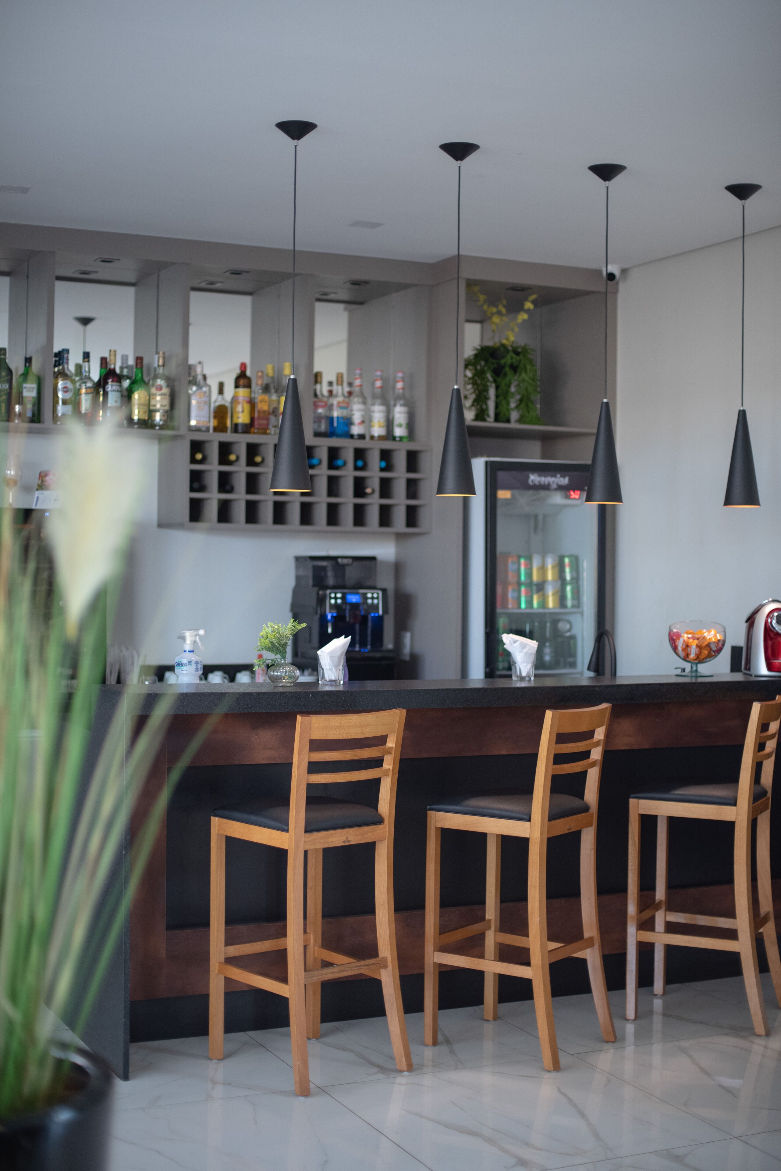 Una cocina moderna con barra, con sillas de madera, un refrigerador y diversos electrodomésticos.