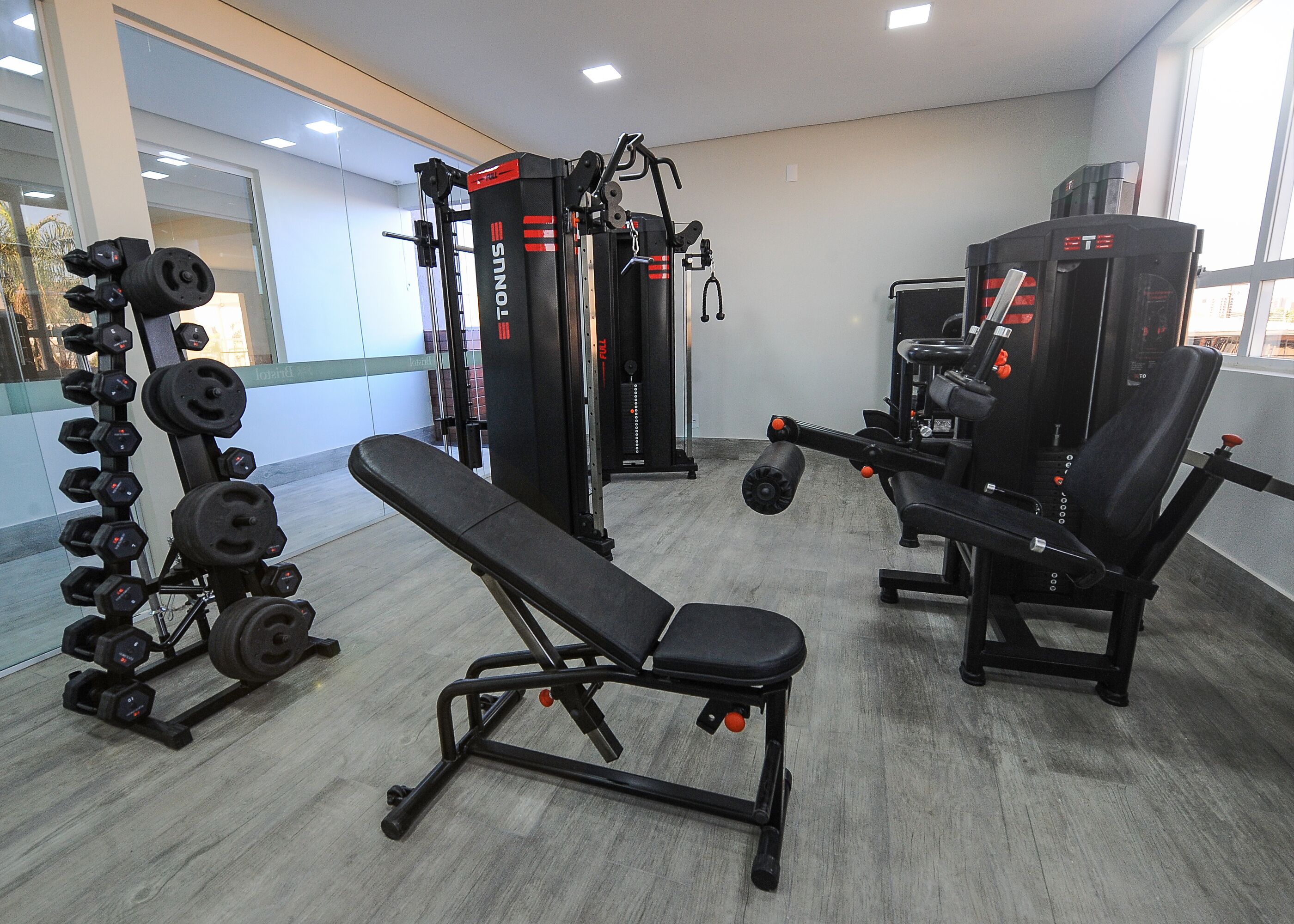 A gym with weightlifting equipment, benches, and a mirror.